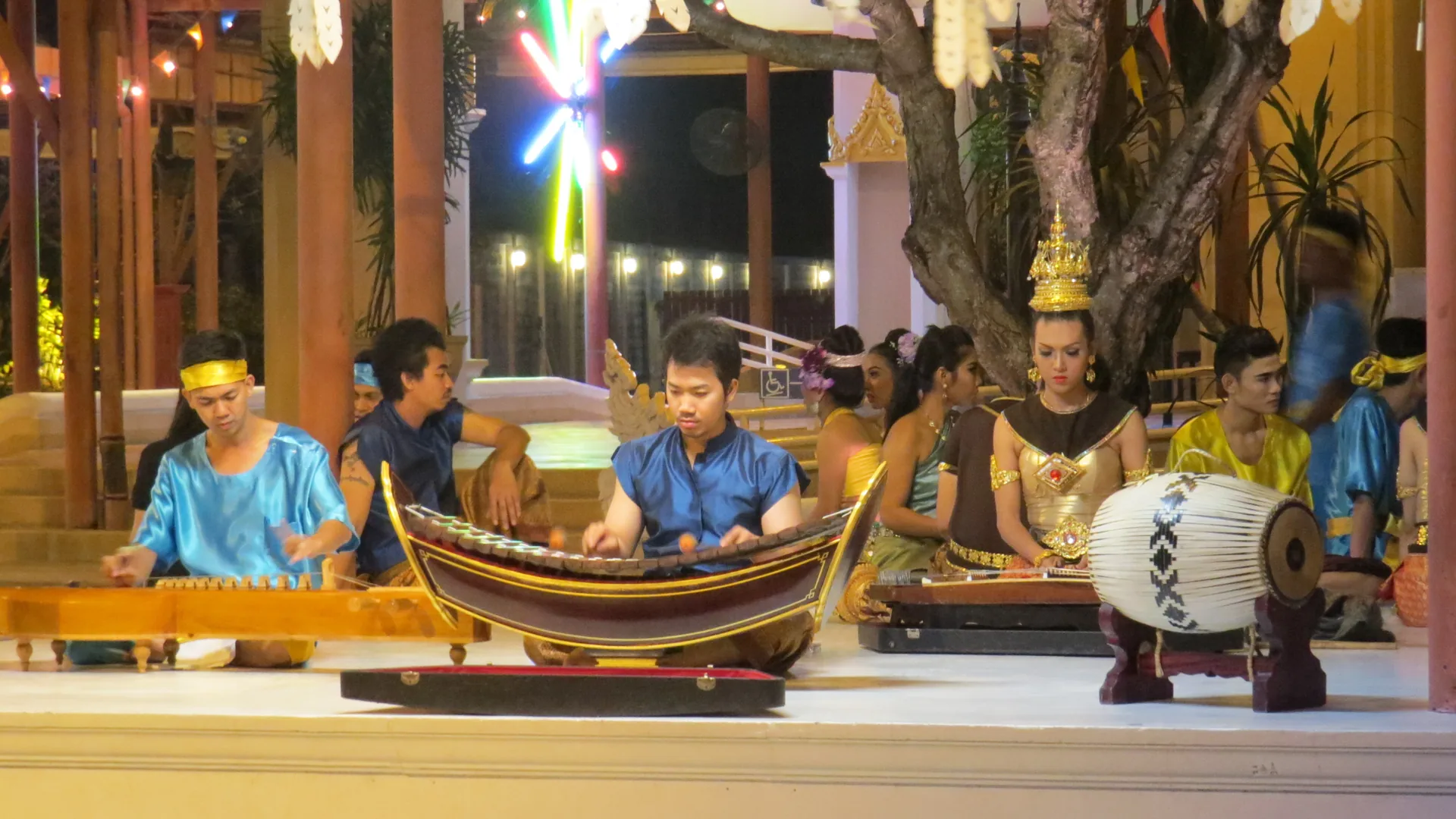 Performers in ornate golden traditional Thai costumes on a grand stage